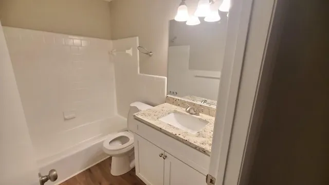 a bathroom with a granite countertop sink a toilet and shower