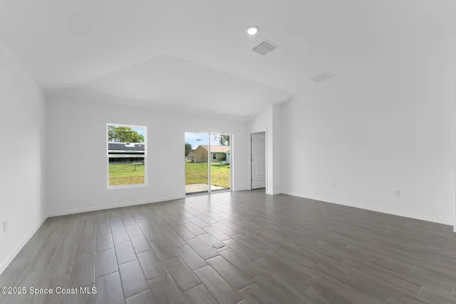 an empty room with wooden floor and window
