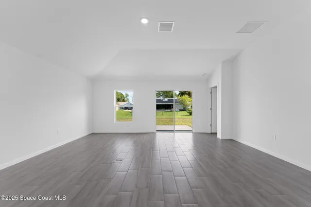 a view of an empty room with a window and wooden floor
