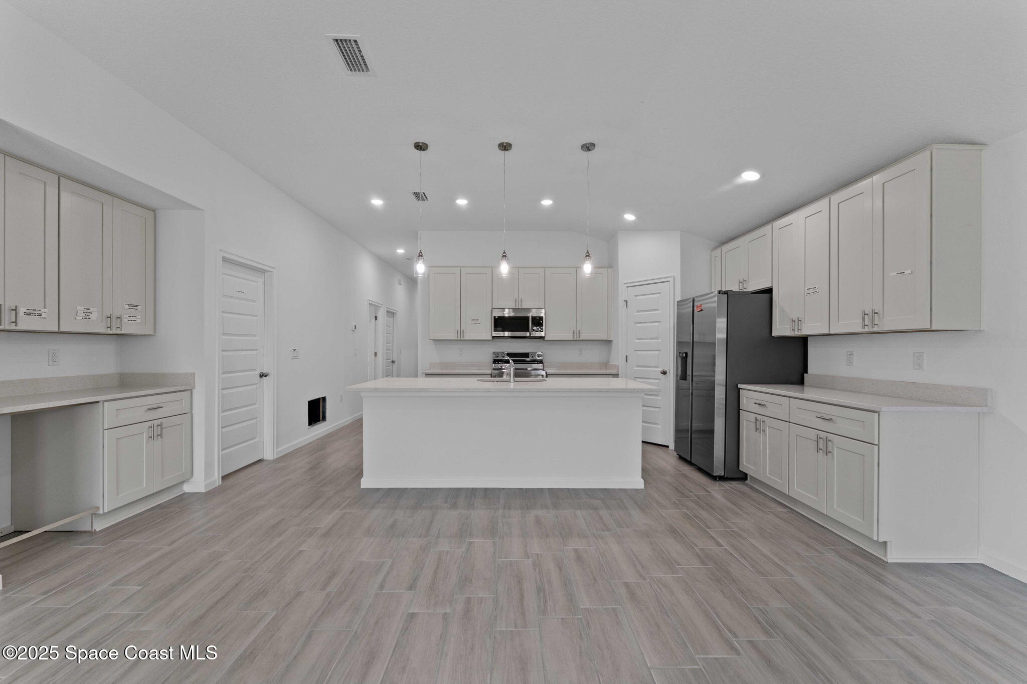 101 Crosspoint Street Southeast Palm Bay, FL 32909 - Photo 9 of 28 a large kitchen with kitchen island a sink a center island stainless steel appliances and a cabinets