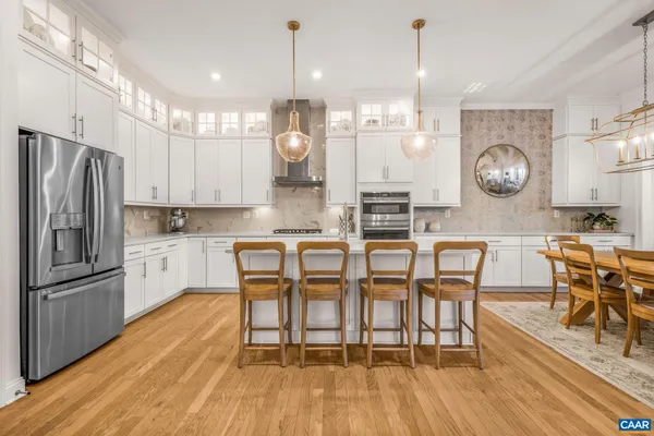 a kitchen with stainless steel appliances granite countertop a refrigerator a sink dishwasher a stove and white cabinets with wooden floor