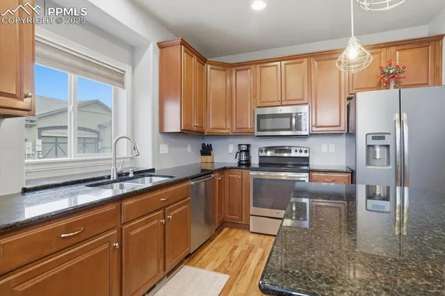 a kitchen with granite countertop a refrigerator stove top oven and sink