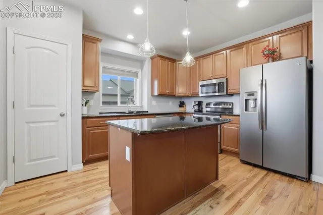 a kitchen with stainless steel appliances granite countertop a refrigerator a sink dishwasher a stove with wooden cabinets and wooden floor