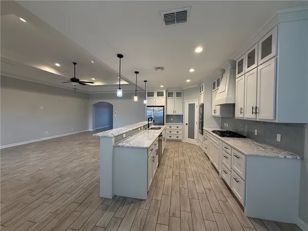 a large kitchen with stainless steel appliances a large counter top a stove and a wooden floors