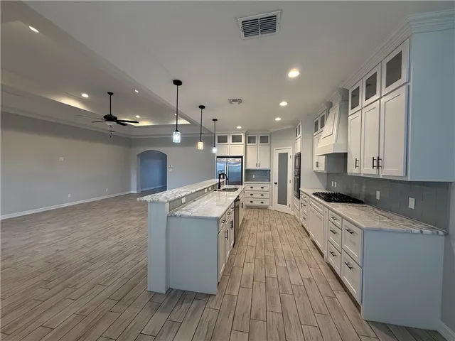 a large kitchen with stainless steel appliances a large counter top a stove and a wooden floors