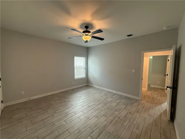 an empty room with wooden floor fan and windows