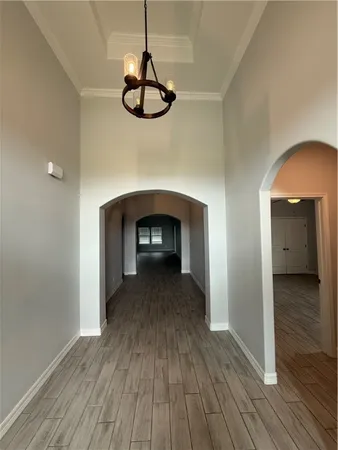 a view of empty room with wooden floor carpet and a chandelier