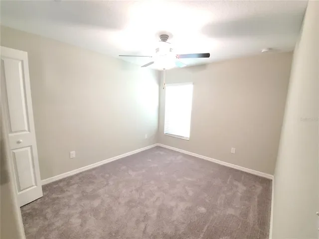 an empty room with a ceiling fan and a window
