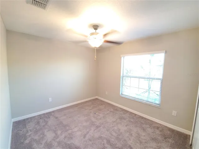 an empty room with a chandelier fan and a window