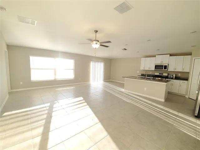 a kitchen with stainless steel appliances kitchen island granite countertop a stove a sink and a refrigerator with white cabinets