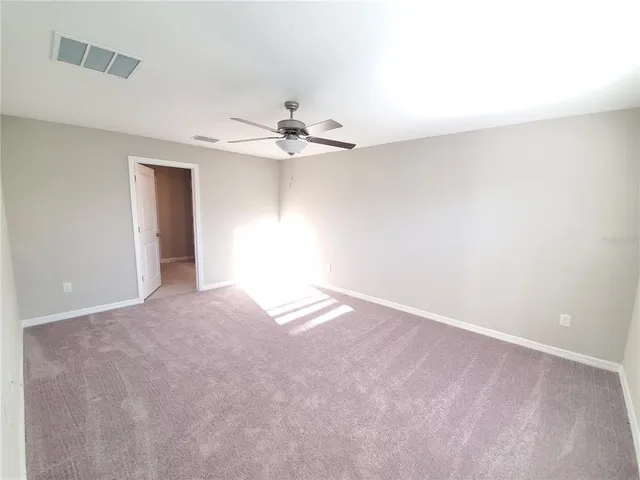 a view of an empty room with a chandelier fan