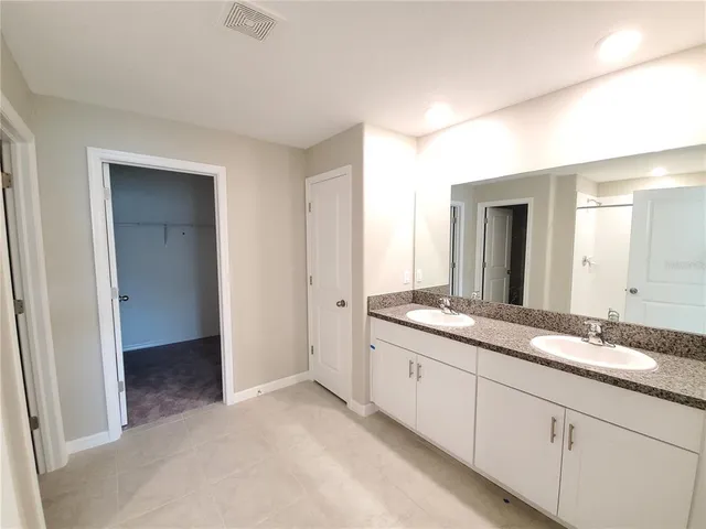 a spacious bathroom with a granite countertop sink and a mirror