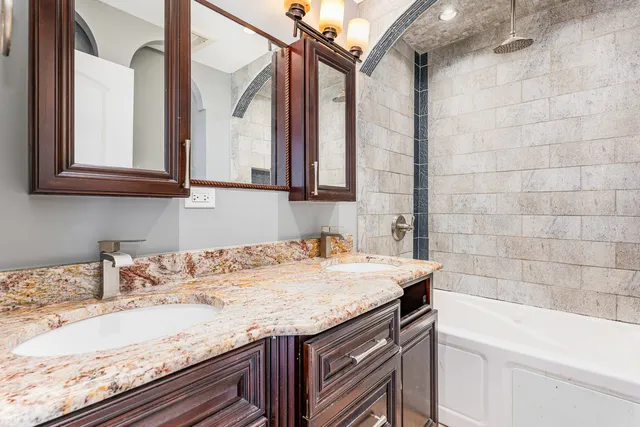 a bathroom with a granite countertop sink and a bathtub