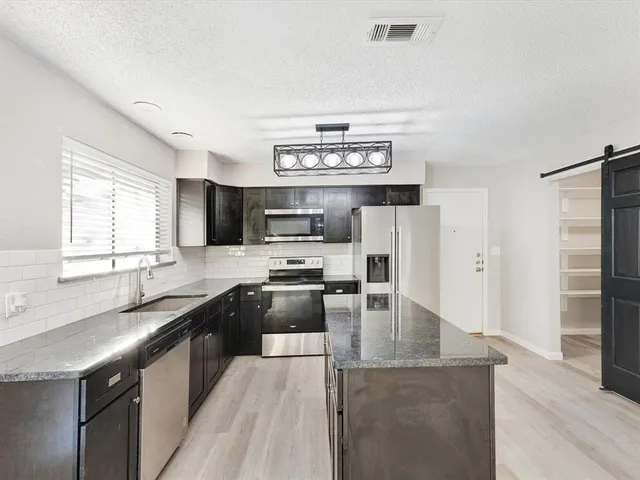 a kitchen with stainless steel appliances granite countertop a sink stove and refrigerator