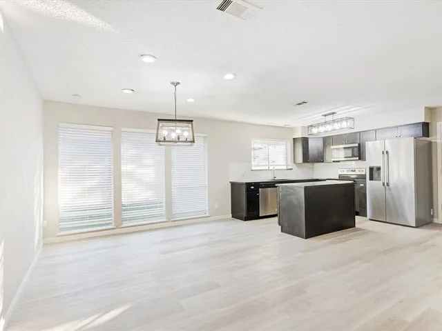 a view of kitchen with stainless steel appliances granite countertop a stove a sink a refrigerator white cabinets and wooden floor