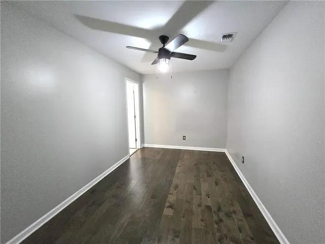 an empty room with wooden floor and ceiling fan