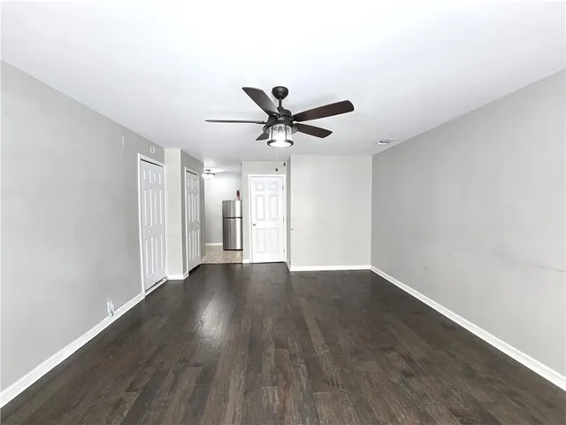 an empty room with wooden floor and ceiling fan