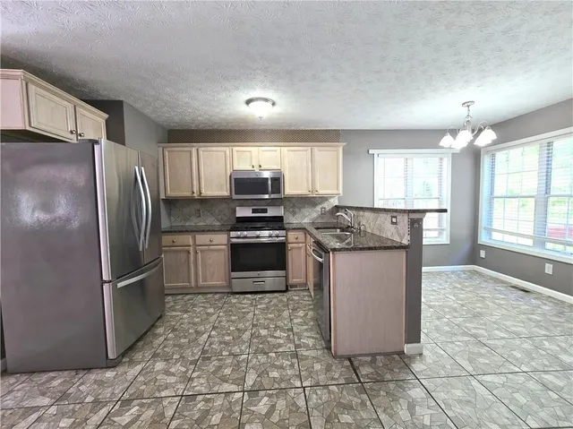 a kitchen with stainless steel appliances granite countertop a refrigerator stove top oven and sink