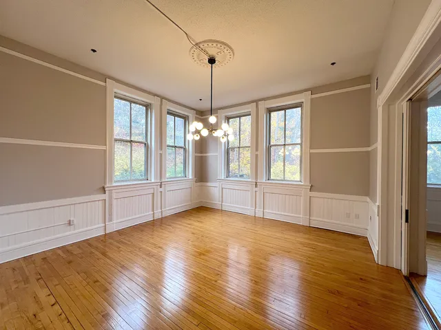 a view of an empty room with a window and wooden floor