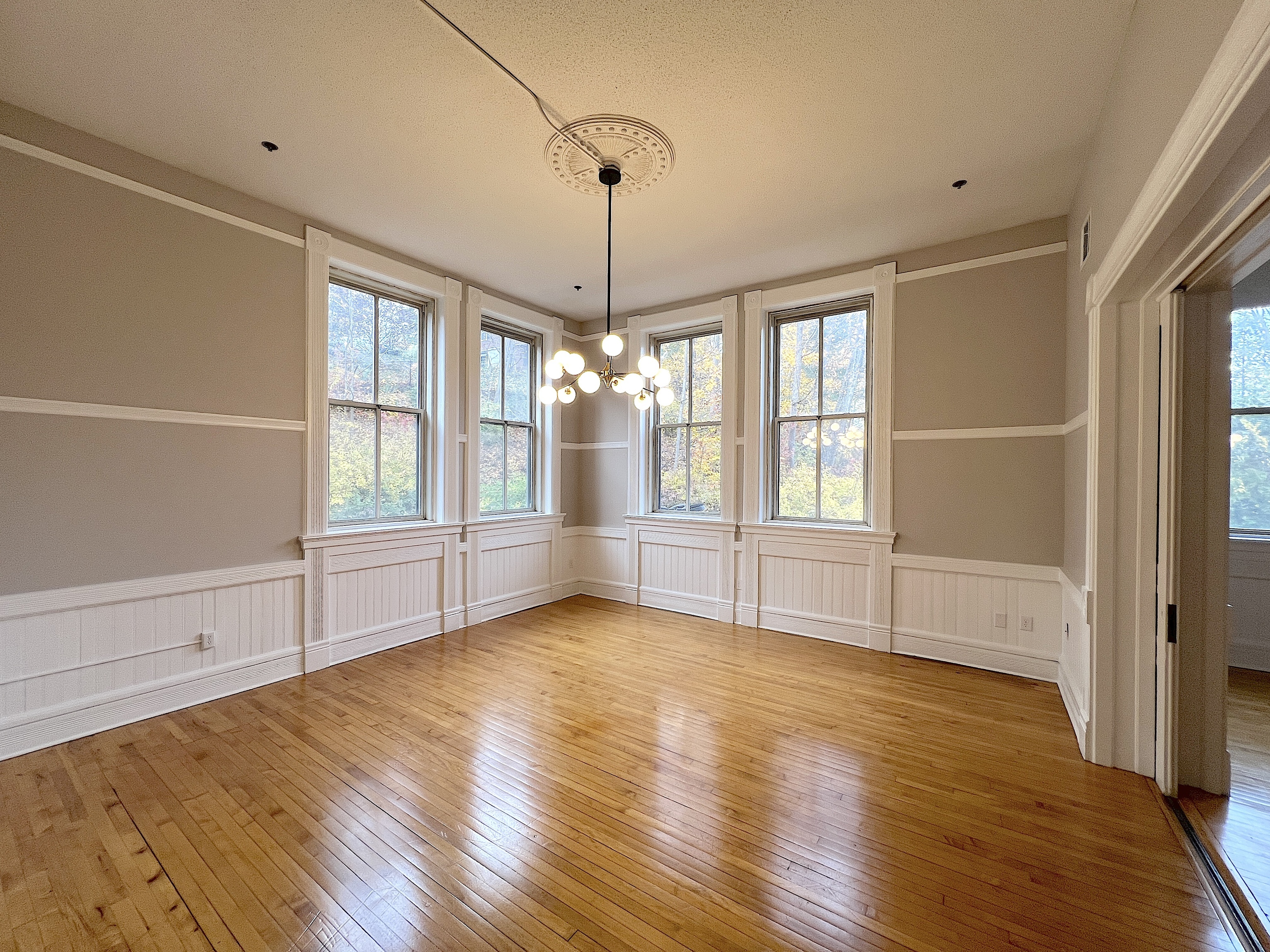 a view of an empty room with a window and wooden floor