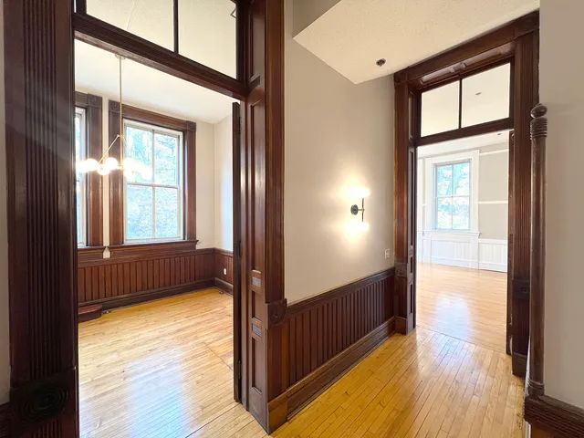 a view of an empty room with wooden floor and a window