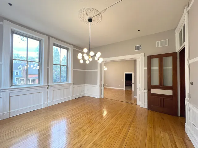 a view of a livingroom with a chandelier wooden floor and windows