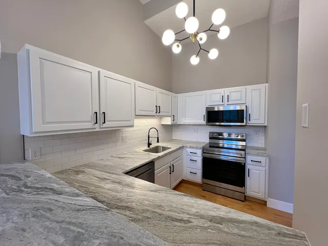 a kitchen with stainless steel appliances granite countertop a sink a stove top oven and cabinets