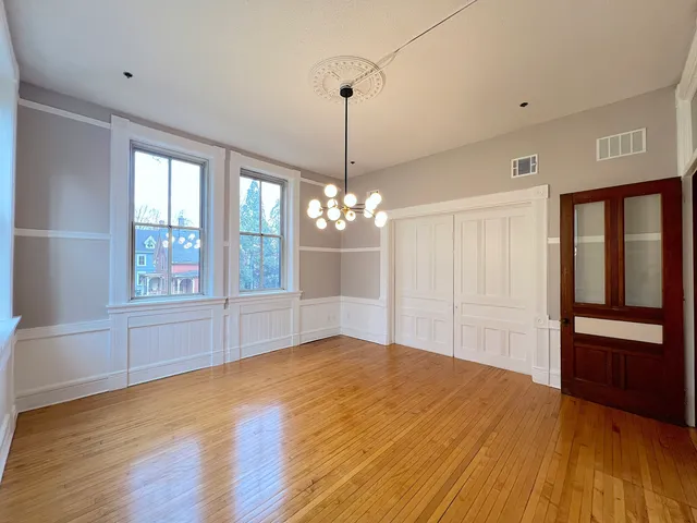 a view of an empty room with window and wooden floor