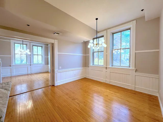 a view of an empty room with window and wooden floor