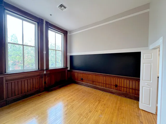 a view of an empty room with wooden floor and windows