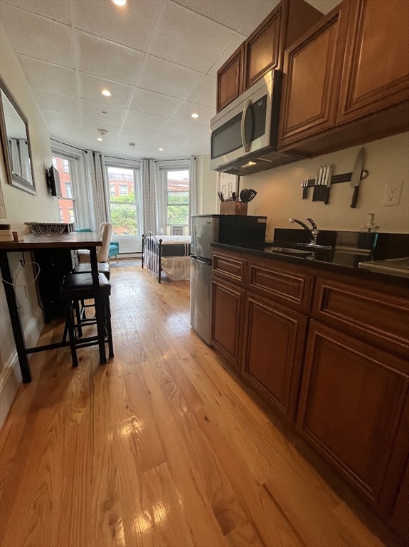 a kitchen with stainless steel appliances granite countertop a sink dishwasher stove and cabinets with wooden floor