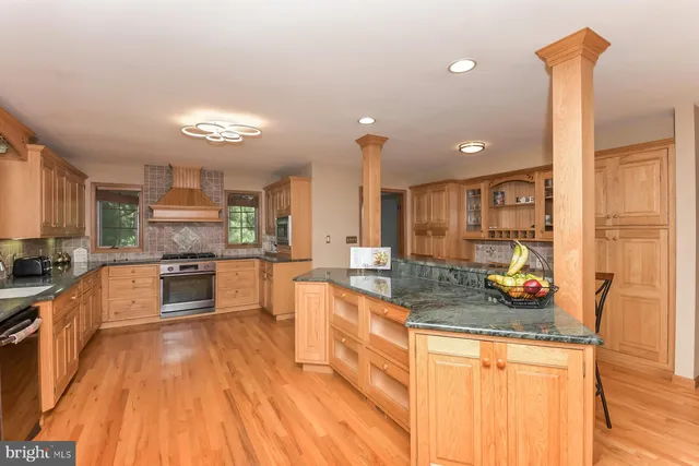 a large kitchen with stainless steel appliances a large counter top a stove a sink a refrigerator and a cabinets