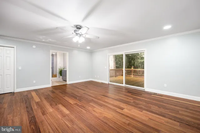 an empty room with wooden floor fan and windows