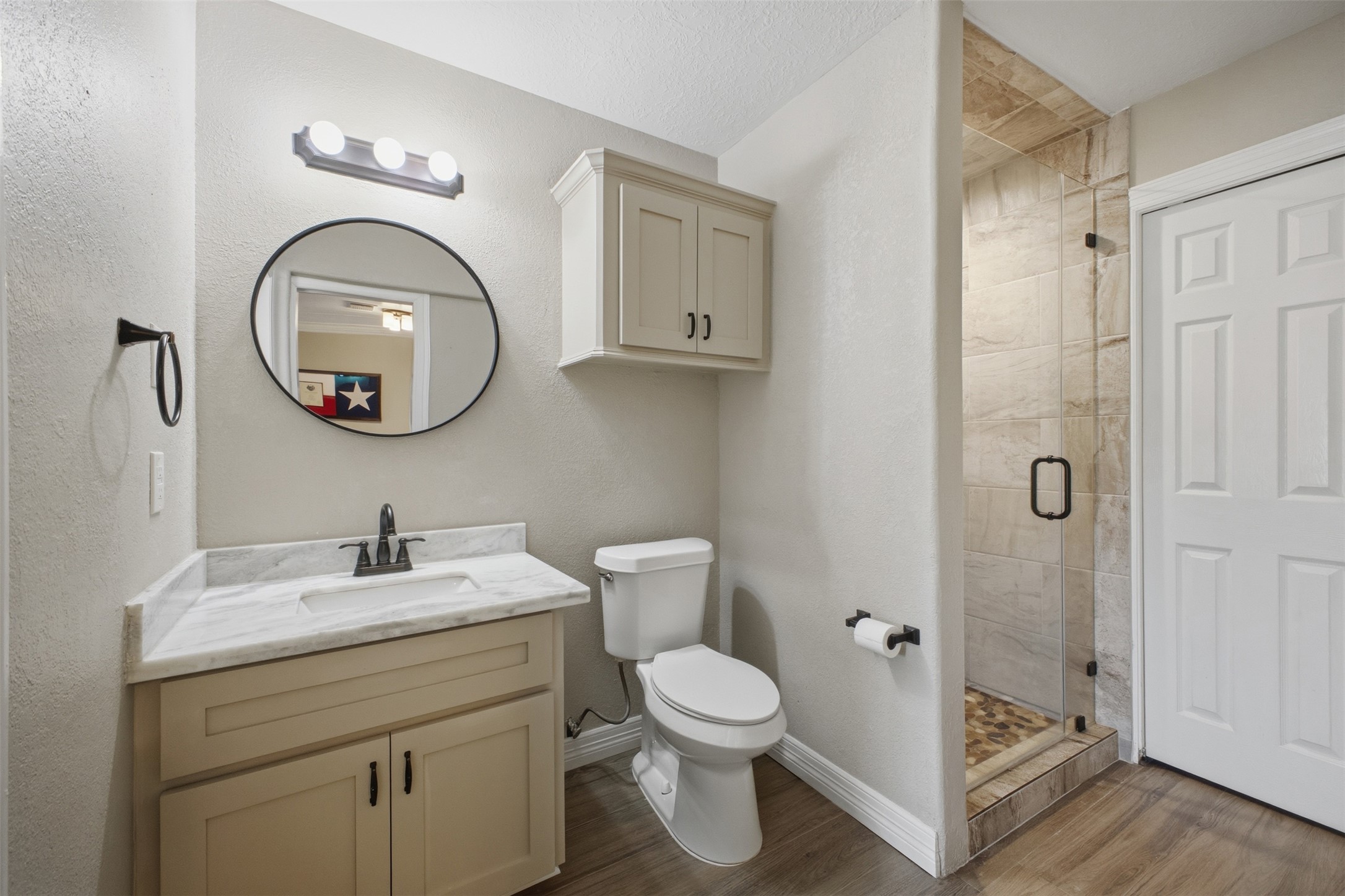 12710 Aries Loop Willis, TX 77318 - Photo 25 of 40 The bathroom features a vanity with a white countertop and a black faucet, a round mirror, and a walk-in shower with a glass enclosure and tiled walls
