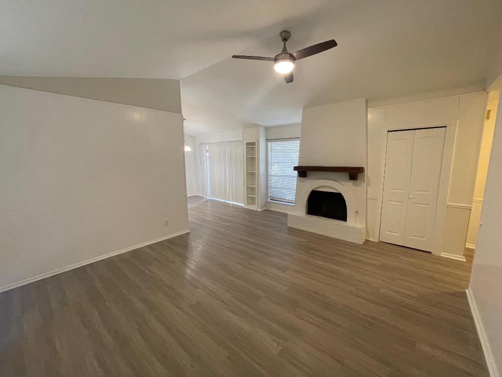 8105 Ceberry Drive, Unit B Austin, TX 78759 - Photo 10 of 12 an empty room with wooden floor a fireplace and windows