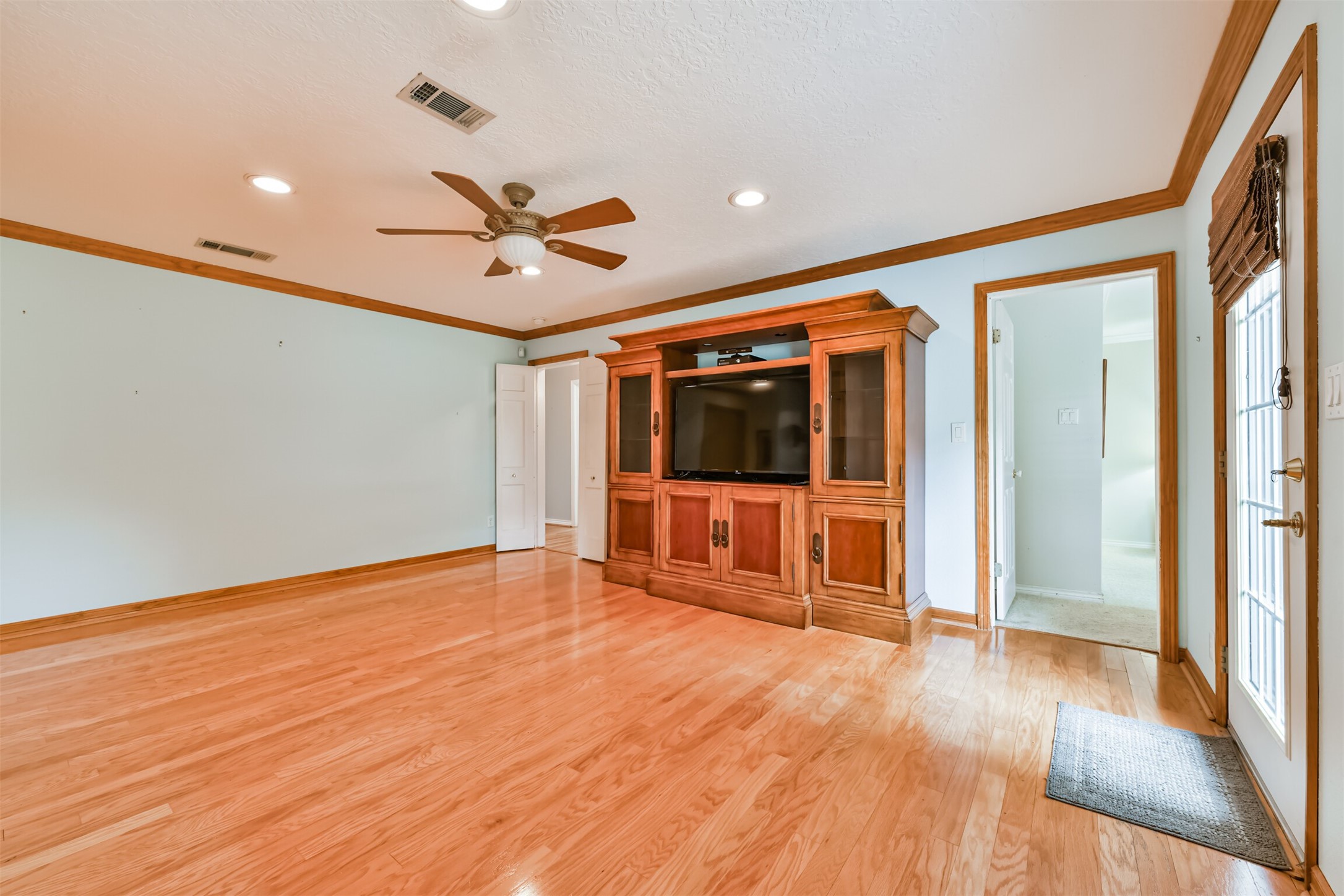 2511 Watts Street Houston, TX 77030 - Photo 16 of 34 Spacious den with hardwood floors, abundant natural light, and a view of the backyard. Features include a ceiling fan and recessed lighting, with easy access to outdoor living.
