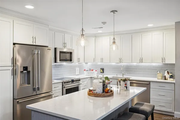 a kitchen with stainless steel appliances a stove a sink a refrigerator a center island and cabinets