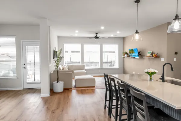 a kitchen with stainless steel appliances kitchen island granite countertop a table chairs a sink dishwasher a refrigerator and cabinets with wooden floor