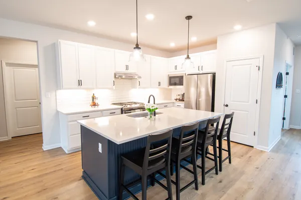 a kitchen that has a sink a center island stainless steel appliances and a chandelier