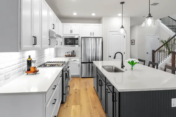 a kitchen with kitchen island a dining table chairs and white cabinets