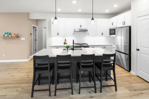 a kitchen with stainless steel appliances kitchen island granite countertop a table chairs and a refrigerator