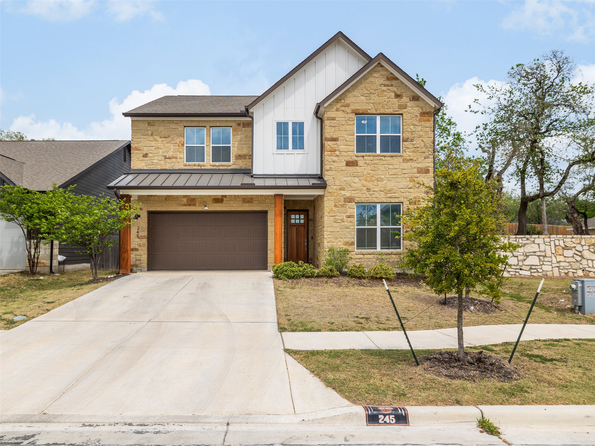 245 Brooks Ranchi Drive Kyle, TX 78640 - Photo 1 of 16 View of front of house with stone siding, board and batten siding, a garage, concrete driveway, and a standing seam roof