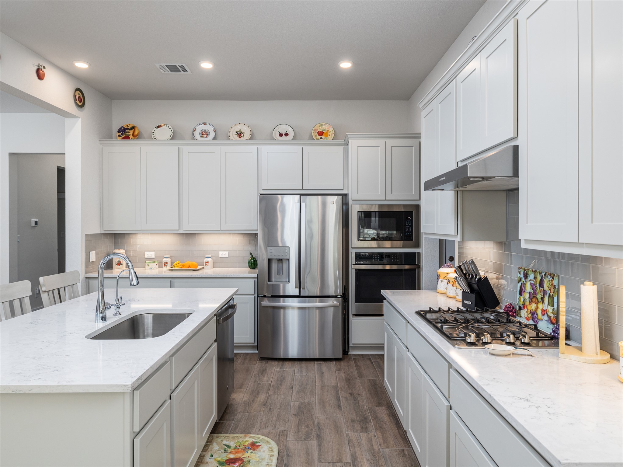 245 Brooks Ranchi Drive Kyle, TX 78640 - Photo 3 of 16 Kitchen with stainless steel appliances, dark wood-style floors, white cabinets, light stone counters, and a kitchen breakfast bar