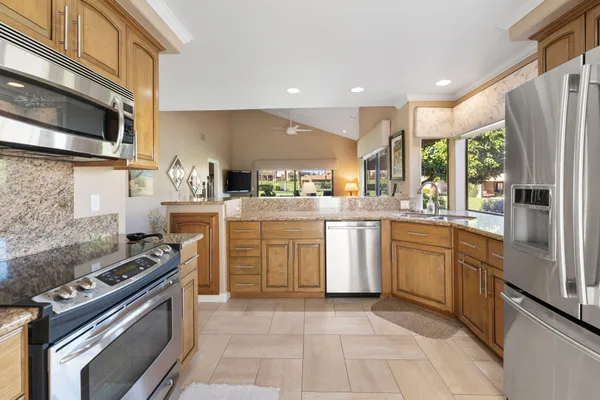 a kitchen with stainless steel appliances granite countertop a stove a sink and a refrigerator