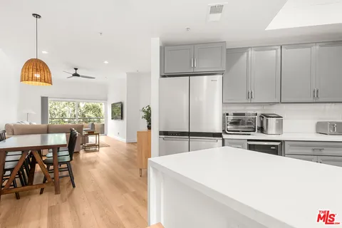 a kitchen with stainless steel appliances a dining table chairs stove and refrigerator