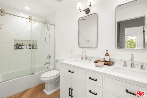 a bathroom with a double vanity sink toilet mirror and shower