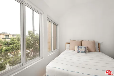 a large white bed in a room next to a window
