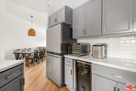 a kitchen with stainless steel appliances granite countertop a refrigerator a stove a sink a dining table and chairs with wooden floor