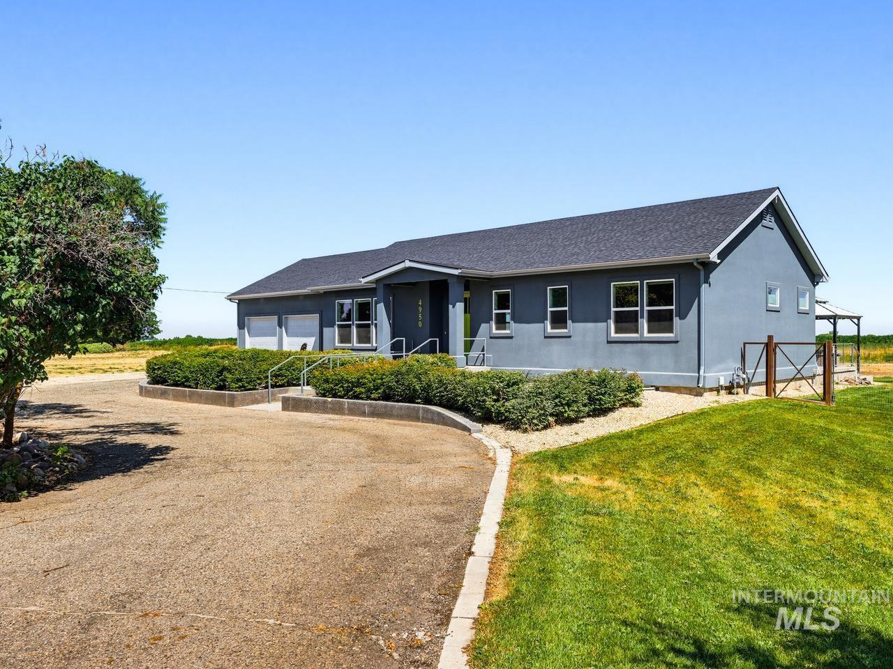 4950 West Columbia Road Nampa, ID 83687 - Photo 2 of 50 Single-story residence featuring a dark asphalt shingle roof, gray stucco exterior, and white-framed windows