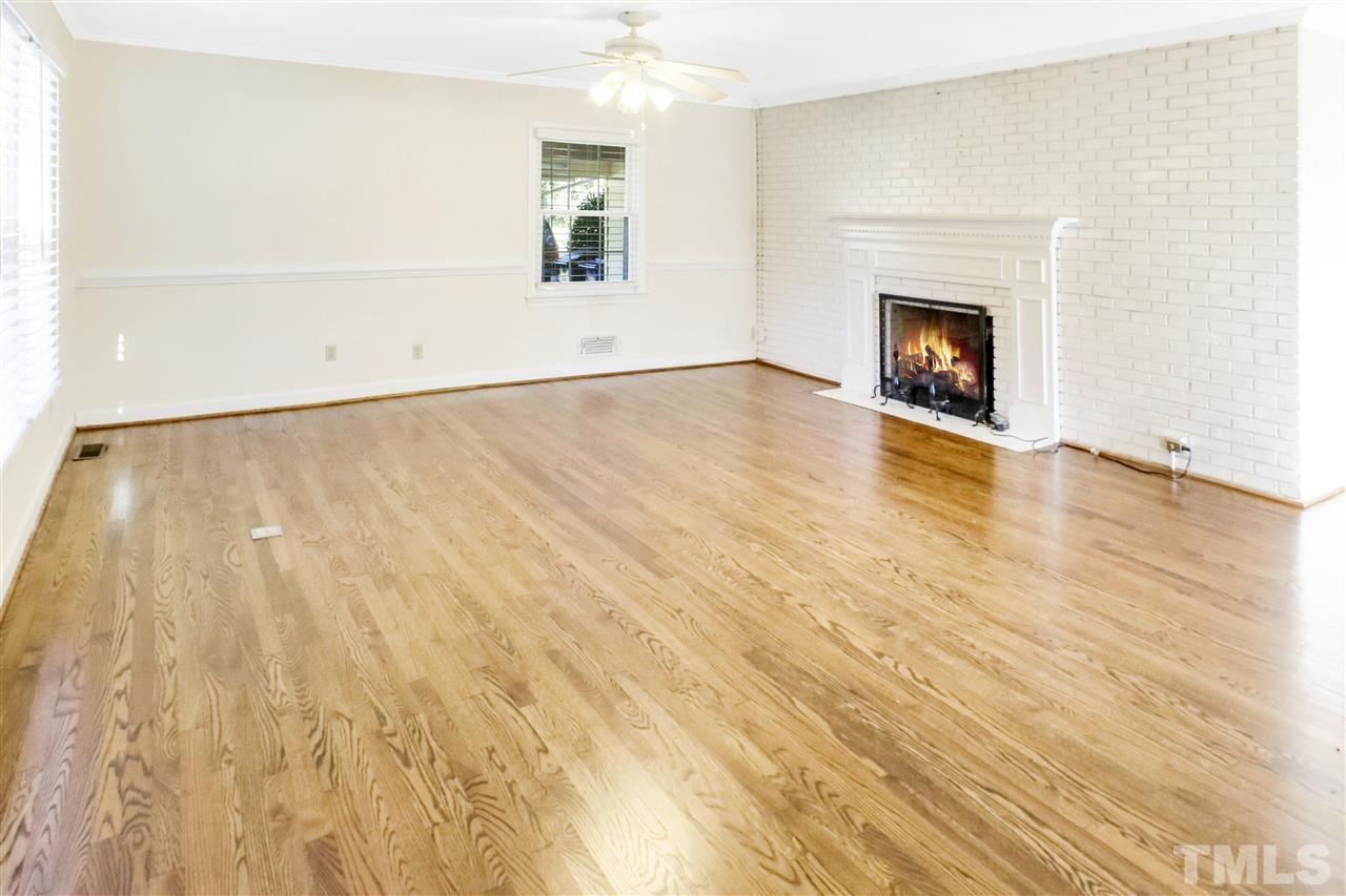 901 Merrie Road Raleigh, NC 27606 - Photo 4 of 18 a view of empty room with wooden floor and fireplace